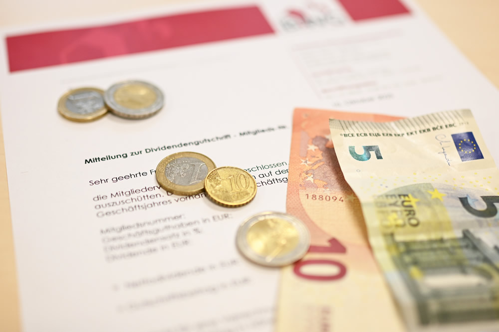 Motivbild zur Dividendengutschrift mit einem förmlichen Anschreiben und ein paar Münzen und Geldscheinen